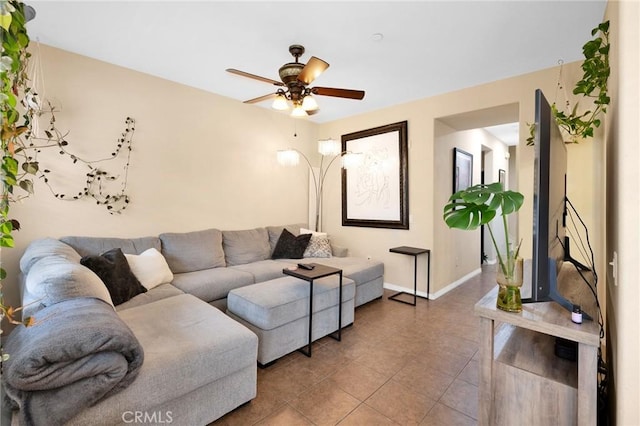 tiled living area with baseboards and a ceiling fan