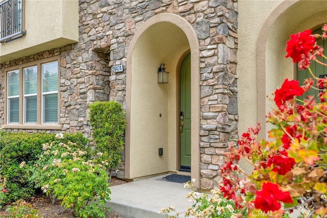 view of exterior entry with stone siding and stucco siding