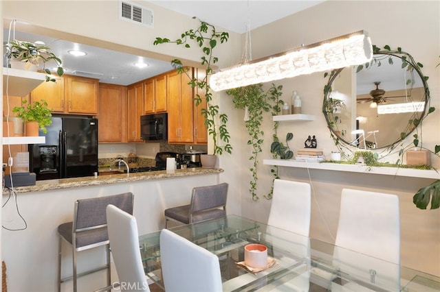 kitchen featuring ceiling fan, a peninsula, a sink, visible vents, and black appliances