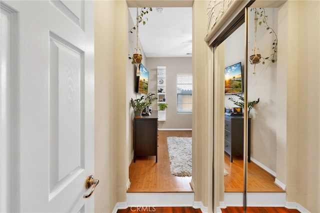 corridor featuring baseboards and wood finished floors