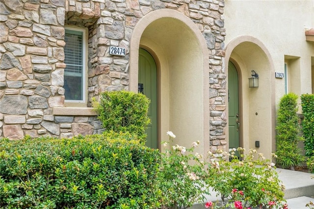 property entrance with stone siding and stucco siding