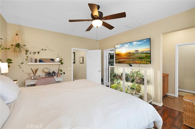 bedroom featuring dark wood-style floors, visible vents, ceiling fan, and baseboards