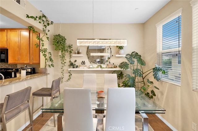 dining area featuring dark tile patterned flooring, visible vents, and baseboards