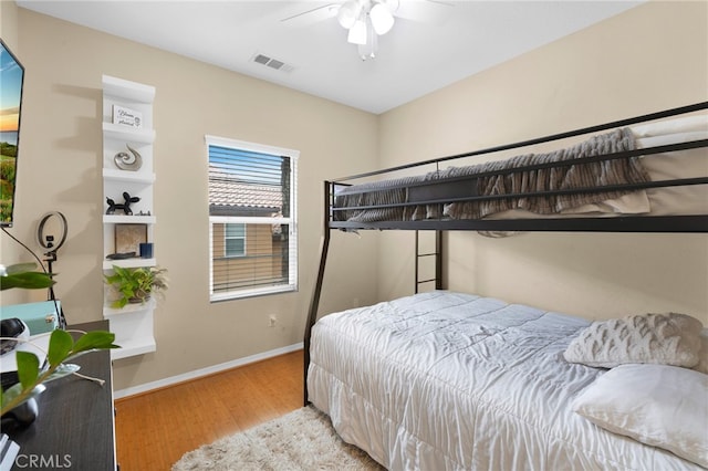 bedroom with baseboards, visible vents, and wood finished floors