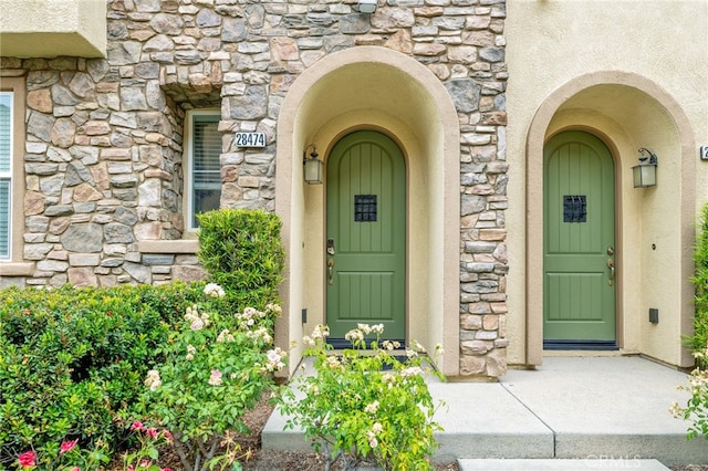 property entrance featuring stone siding and stucco siding