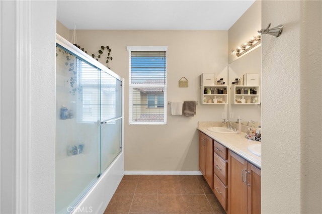 full bathroom featuring tile patterned flooring, bath / shower combo with glass door, a sink, baseboards, and double vanity