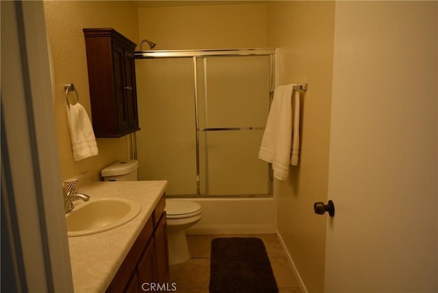 full bathroom with combined bath / shower with glass door, vanity, tile patterned floors, and toilet