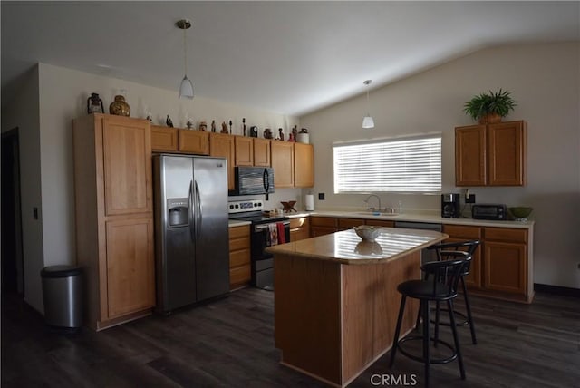 kitchen with dark wood-type flooring, pendant lighting, vaulted ceiling, and appliances with stainless steel finishes