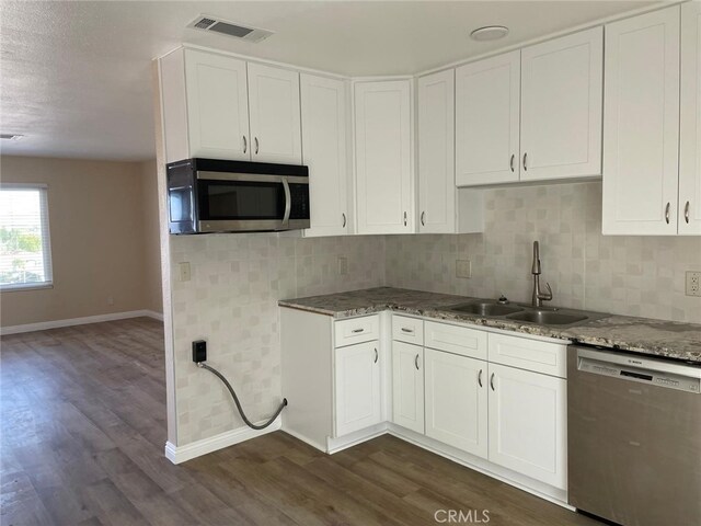 kitchen with appliances with stainless steel finishes, white cabinetry, dark wood-type flooring, and sink