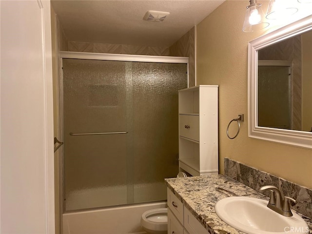 full bathroom with vanity, combined bath / shower with glass door, a textured ceiling, and toilet