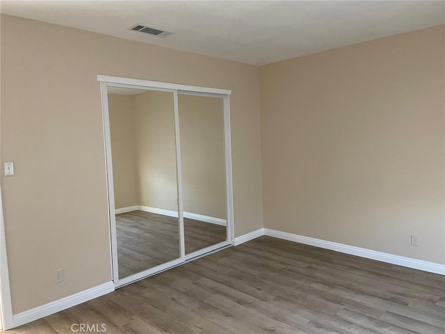 unfurnished bedroom featuring wood-type flooring and a closet