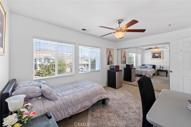 carpeted bedroom with a closet, multiple windows, and ceiling fan