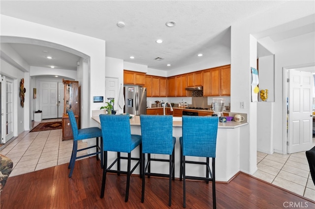 kitchen featuring light wood-type flooring, kitchen peninsula, and stainless steel fridge with ice dispenser