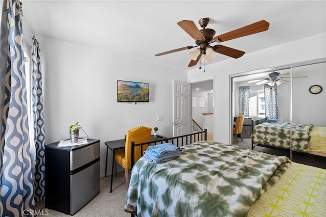 carpeted bedroom with stainless steel refrigerator, ceiling fan, and a closet