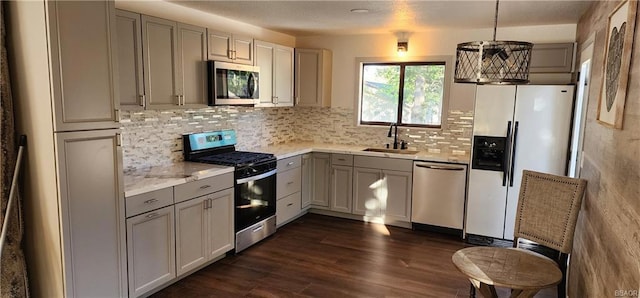 kitchen featuring sink, dark hardwood / wood-style flooring, stainless steel appliances, pendant lighting, and a chandelier