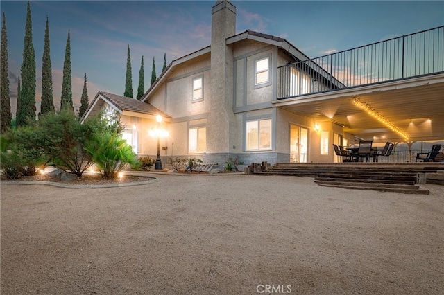 back house at dusk featuring a patio