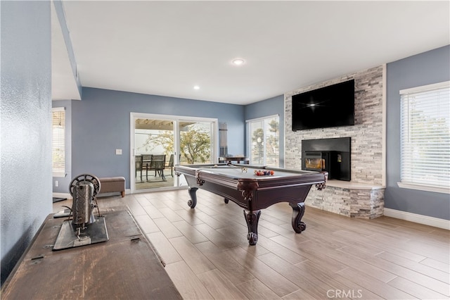 recreation room with pool table, a fireplace, and light wood-type flooring