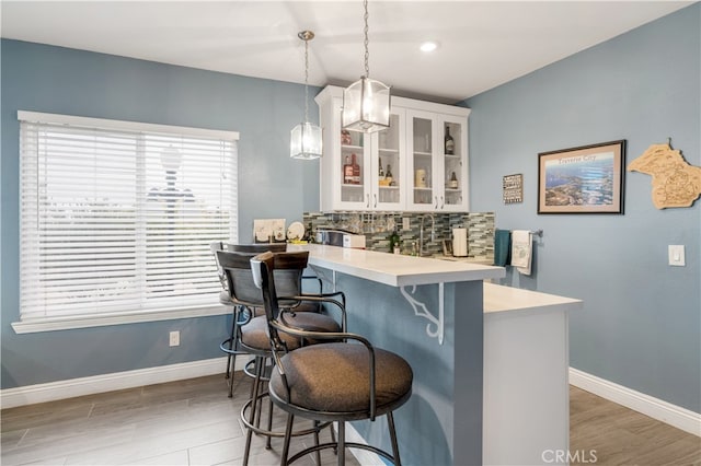 bar with white cabinetry, decorative light fixtures, backsplash, and hardwood / wood-style flooring