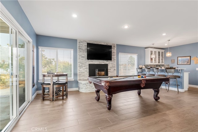 rec room with a stone fireplace, light hardwood / wood-style flooring, and pool table