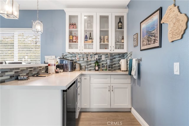 bar featuring white cabinets, hanging light fixtures, backsplash, light hardwood / wood-style floors, and sink