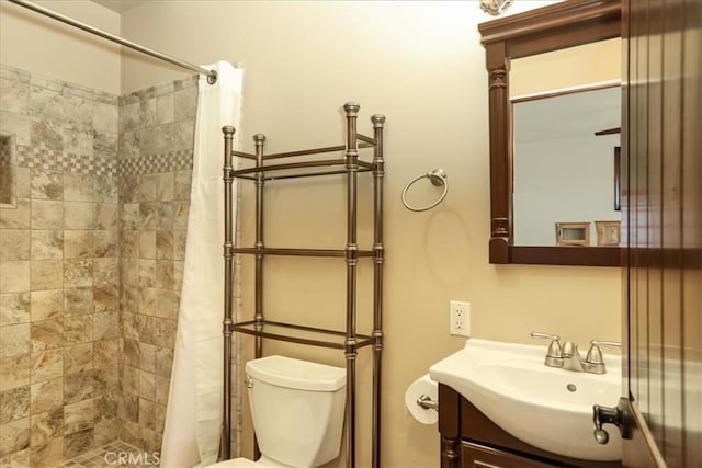 bathroom with toilet, vanity, and tiled shower