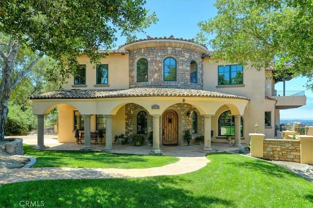 back of house with a patio area, a lawn, stucco siding, and stone siding