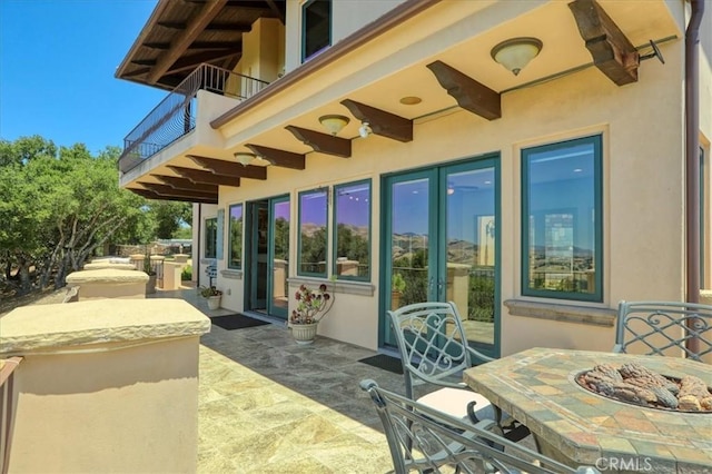 view of patio featuring an outdoor fire pit and a balcony