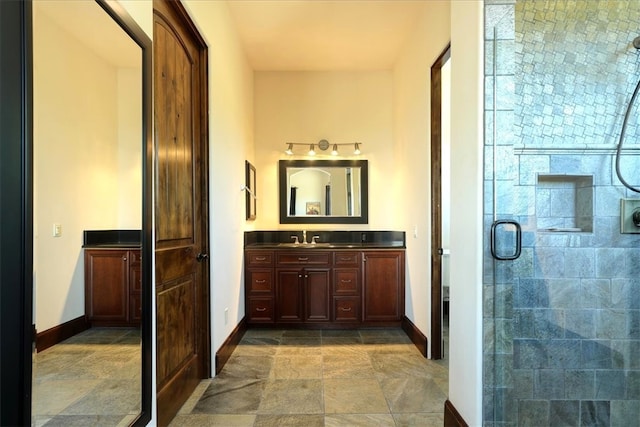 full bathroom with a shower stall, baseboards, stone finish floor, and vanity