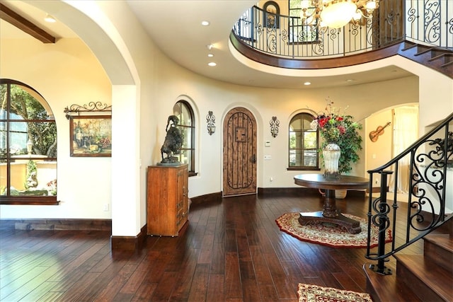 foyer entrance with stairway, arched walkways, hardwood / wood-style flooring, and an inviting chandelier
