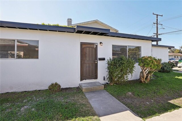 18508 Mansel Ave, Redondo Beach, CA 90278 - view of front facade with stucco siding, a chimney, and a front lawn