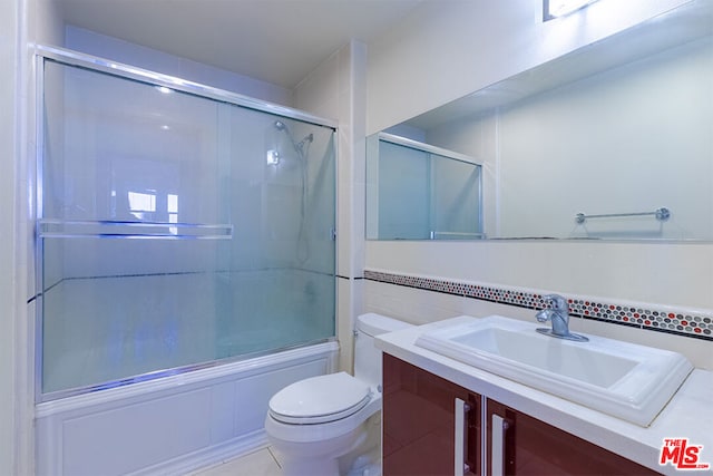 full bathroom with bath / shower combo with glass door, tile patterned flooring, vanity, and toilet