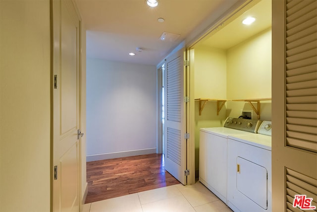 clothes washing area with independent washer and dryer and light wood-type flooring