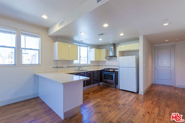 kitchen featuring sink, wood-type flooring, wall chimney exhaust hood, stainless steel range oven, and white fridge