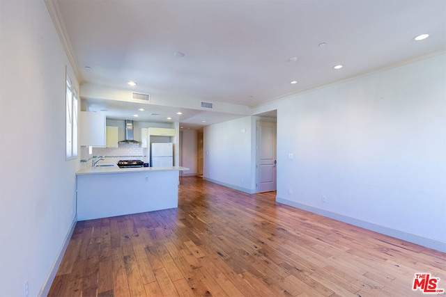 unfurnished living room featuring light hardwood / wood-style floors, crown molding, and sink