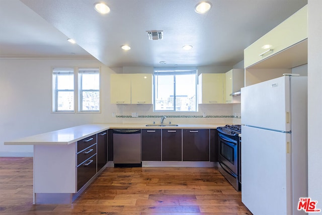 kitchen with kitchen peninsula, dark brown cabinetry, dark wood-type flooring, and stainless steel appliances