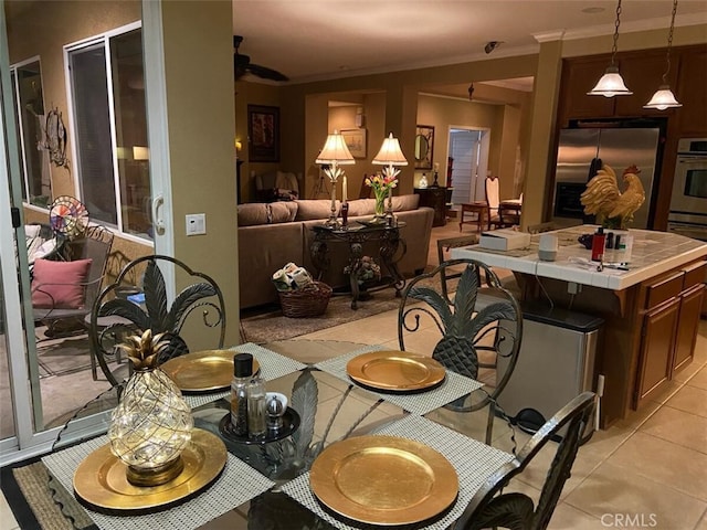 tiled dining space featuring ceiling fan and ornamental molding