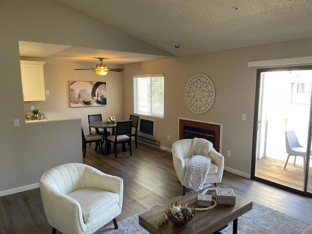 living room featuring dark hardwood / wood-style flooring, ceiling fan, vaulted ceiling, and a textured ceiling