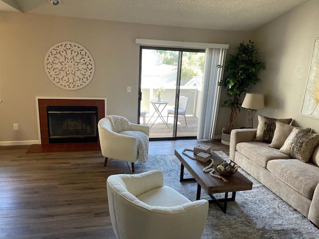 living room with dark hardwood / wood-style flooring, a tiled fireplace, and a textured ceiling