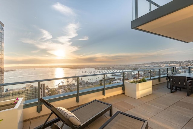 balcony at dusk featuring a water view