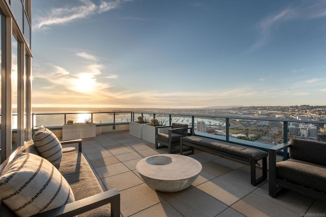 patio terrace at dusk featuring a balcony and a water view