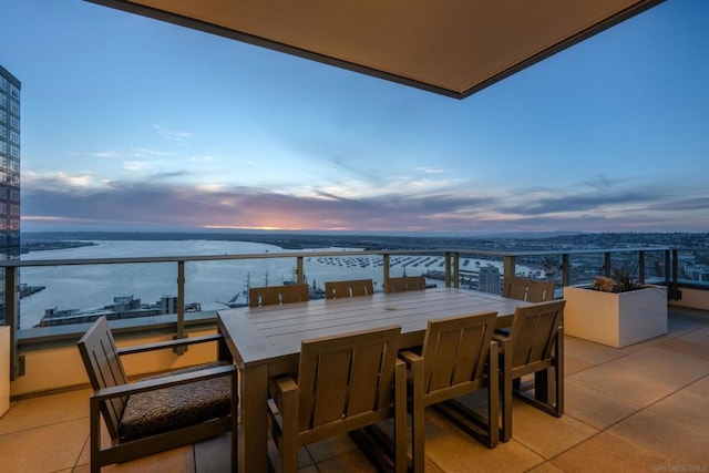 balcony at dusk featuring a water view