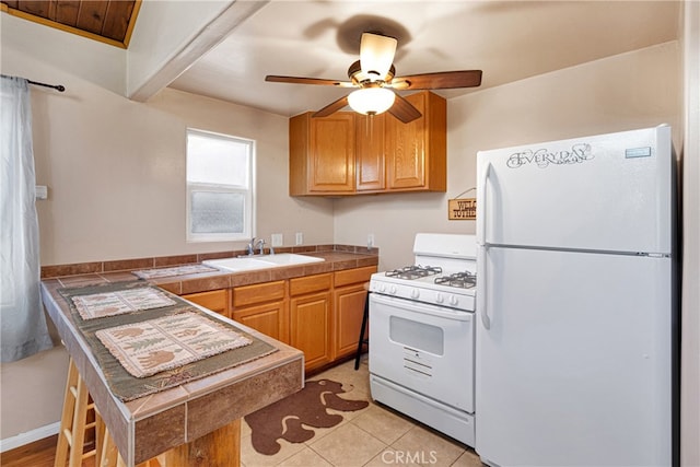 kitchen featuring ceiling fan, light tile patterned floors, sink, white appliances, and tile countertops