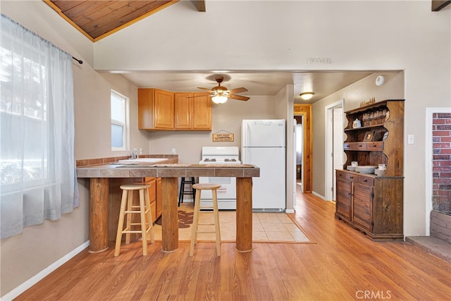 kitchen with a breakfast bar, lofted ceiling, light hardwood / wood-style flooring, white appliances, and ceiling fan