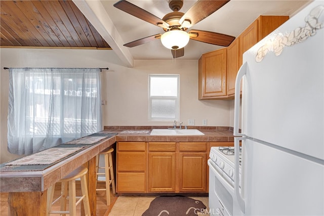 kitchen featuring ceiling fan, beamed ceiling, light tile patterned floors, sink, and white appliances