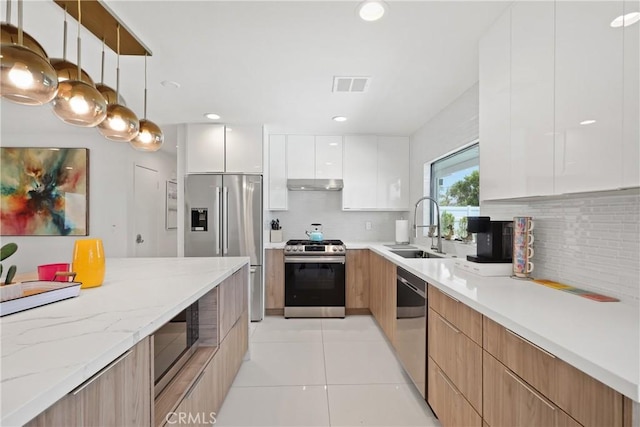 kitchen with stainless steel appliances, white cabinetry, a sink, and modern cabinets