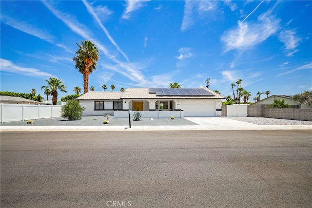 ranch-style home featuring a garage and solar panels