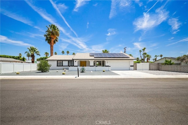 view of front of property with a garage, solar panels, concrete driveway, and fence private yard