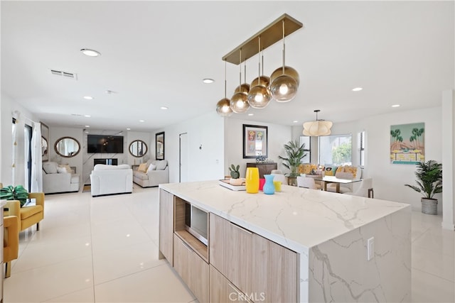 kitchen featuring decorative light fixtures, modern cabinets, visible vents, open floor plan, and light stone countertops