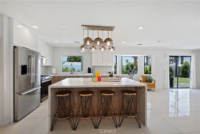 kitchen featuring a kitchen bar, a center island, stainless steel appliances, and white cabinets