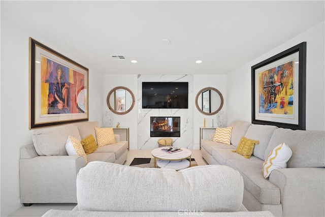 living room featuring recessed lighting, visible vents, and a high end fireplace